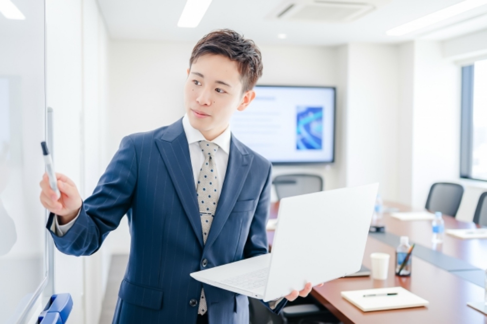 パソコンを持ちながら話す男性