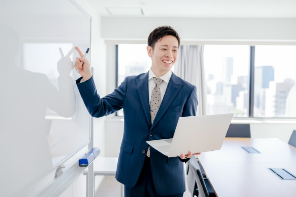 パソコンを持ちながら話をする男性