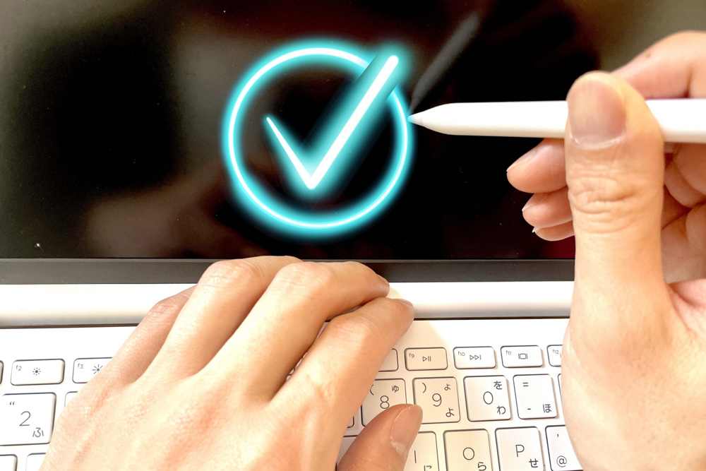 パソコンとペンを持つ手